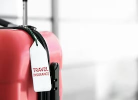 Credit cards with CFAR travel insurance - Suitcase with travel insurance tag - IDFC FIRST Bank